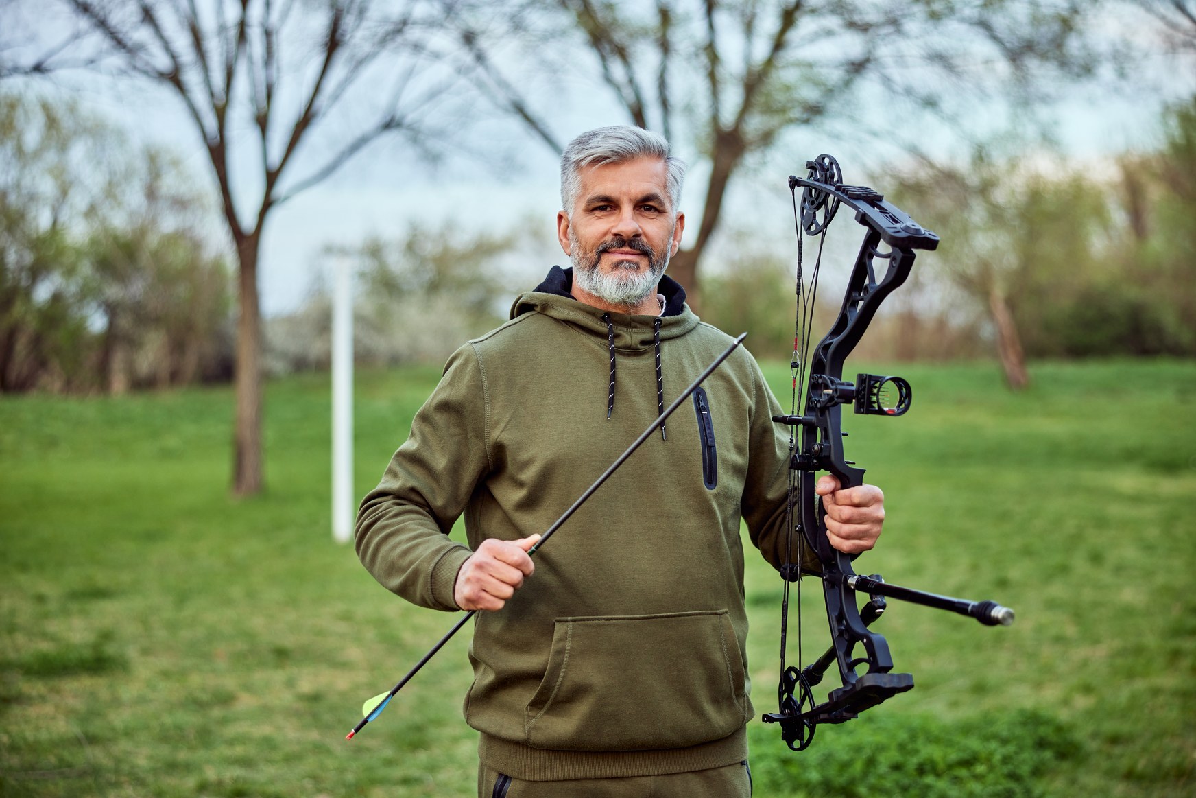 Bowhunter carrying a compound bow through a forest